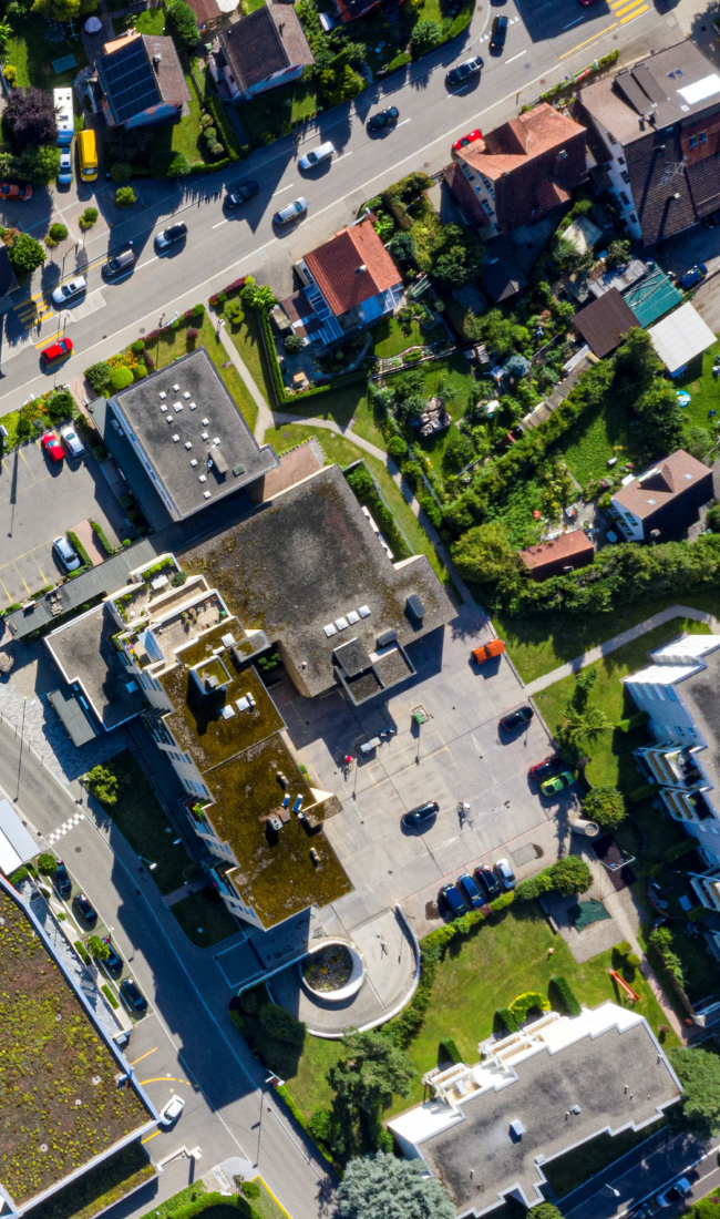 A top-down view of suburban houses and commercial buildings in a lush, green neighborhood.